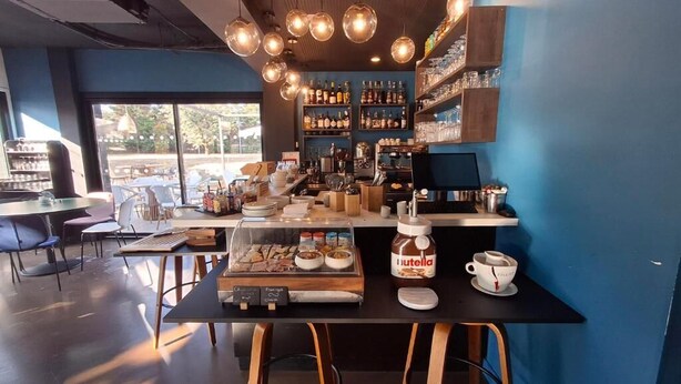 Um café moderno com um espaço para café, um pote de Nutella e vista para a rua.