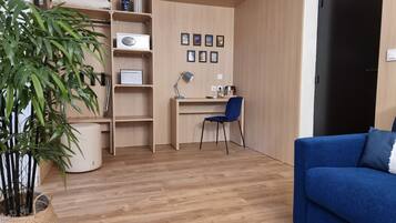 A room with a wooden desk, a chair, a blue sofa, and a potted plant.