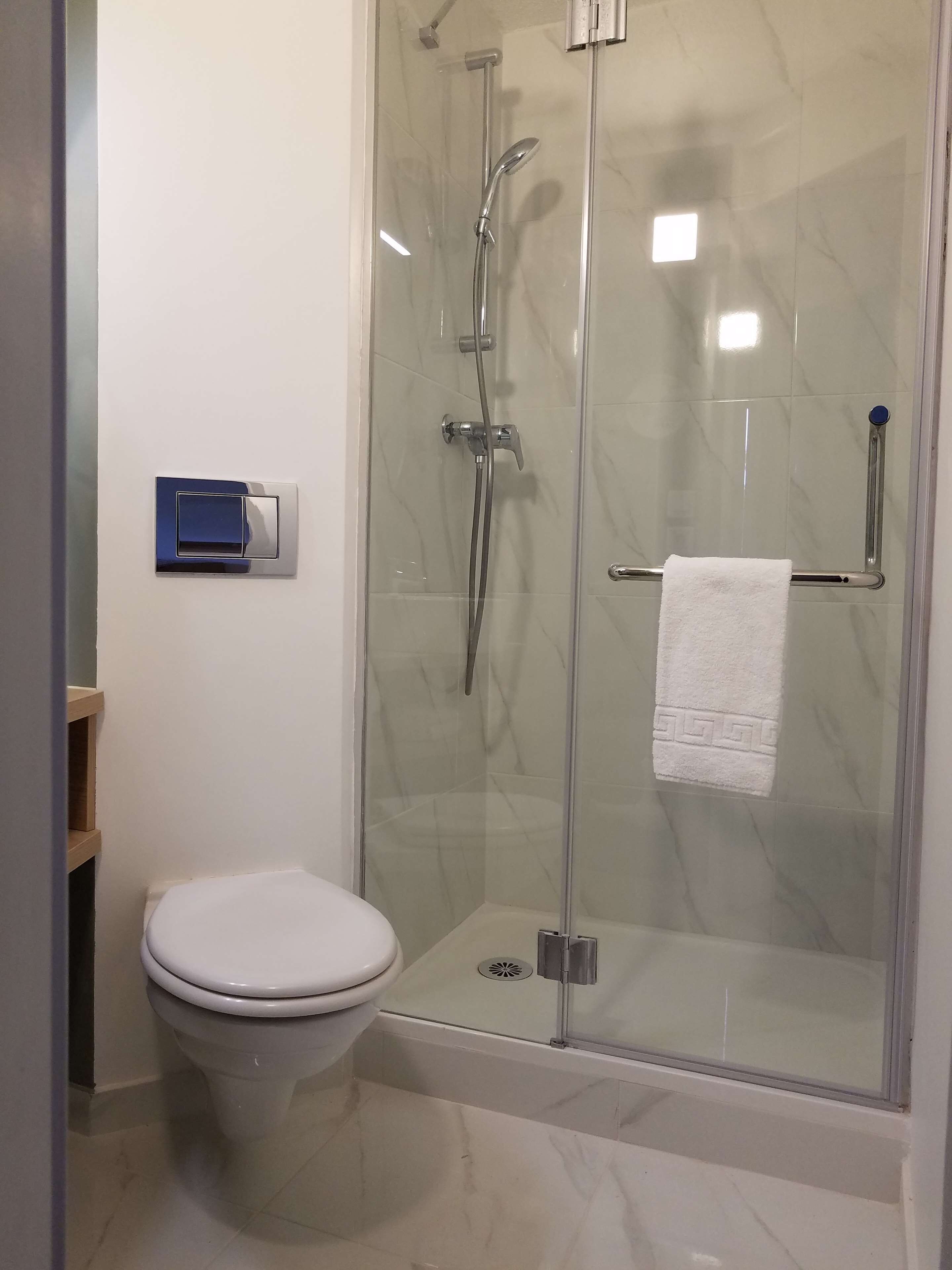 Une salle de bain moderne avec une douche à parois de verre, des toilettes et un porte-serviettes.