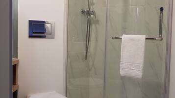 Une salle de bain moderne avec une douche à parois de verre, des toilettes et un porte-serviettes.
