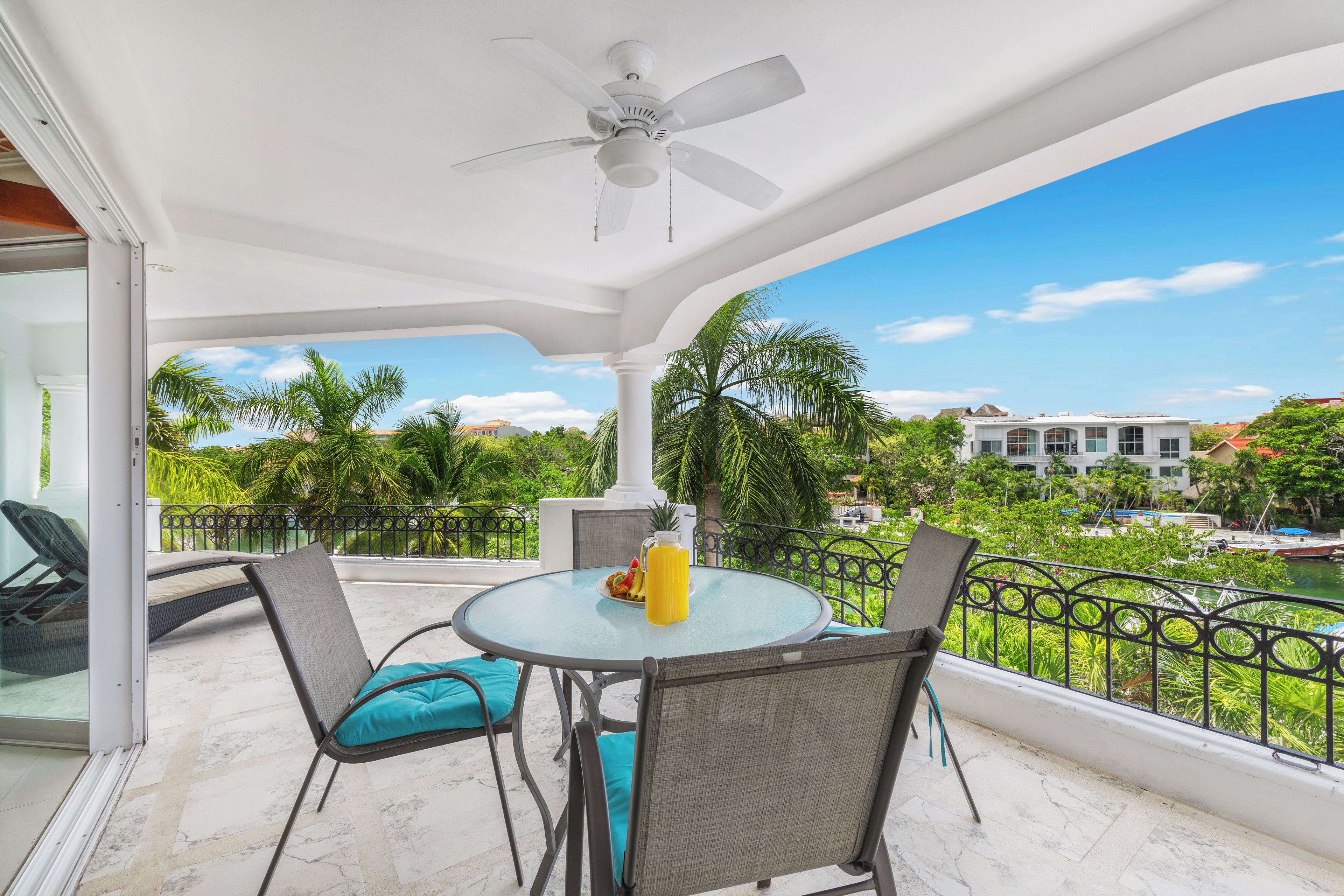 A balcony with a table, chairs, and a ceiling fan.