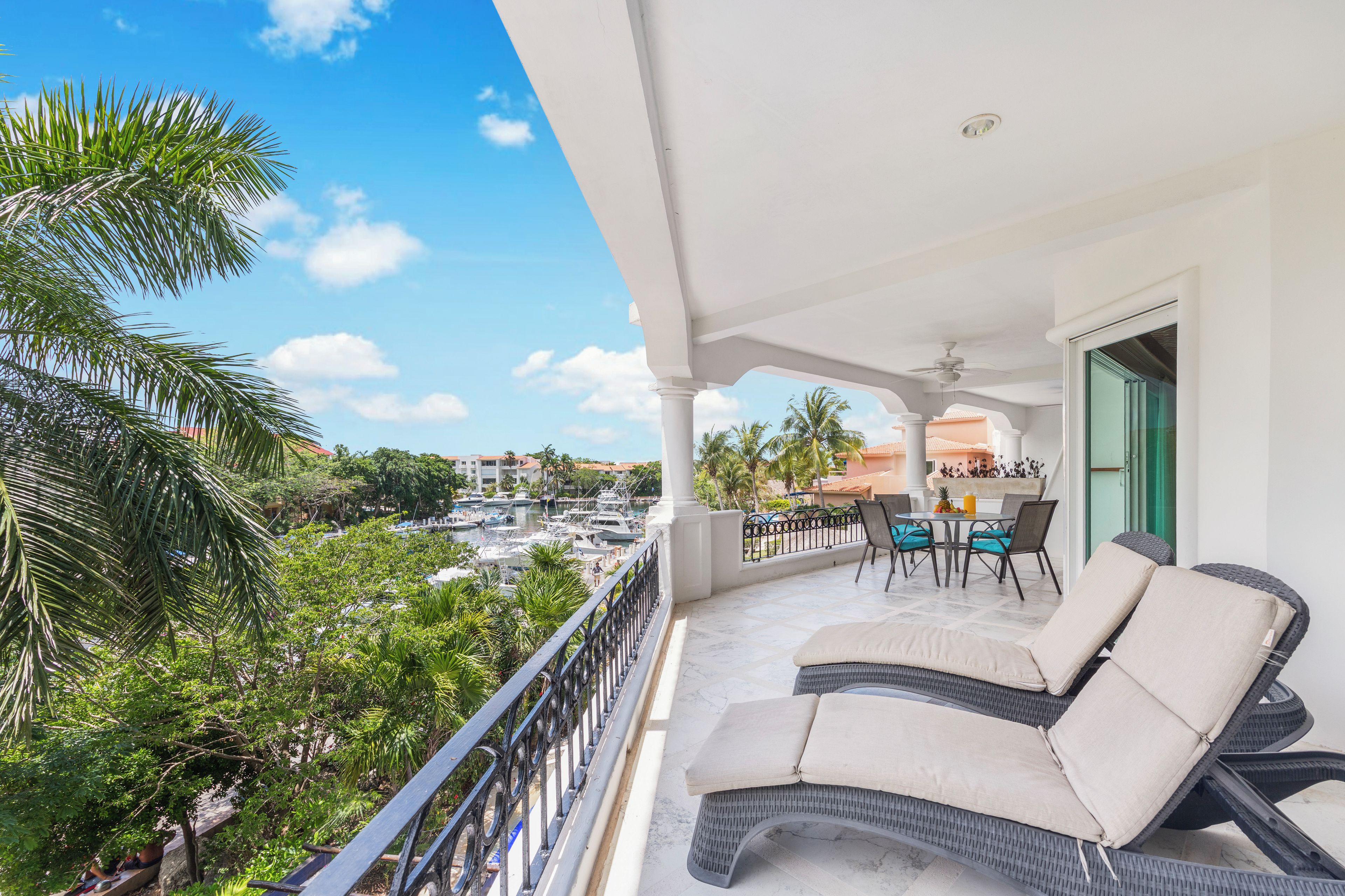 A balcony with outdoor seating, overlooking a marina and buildings.