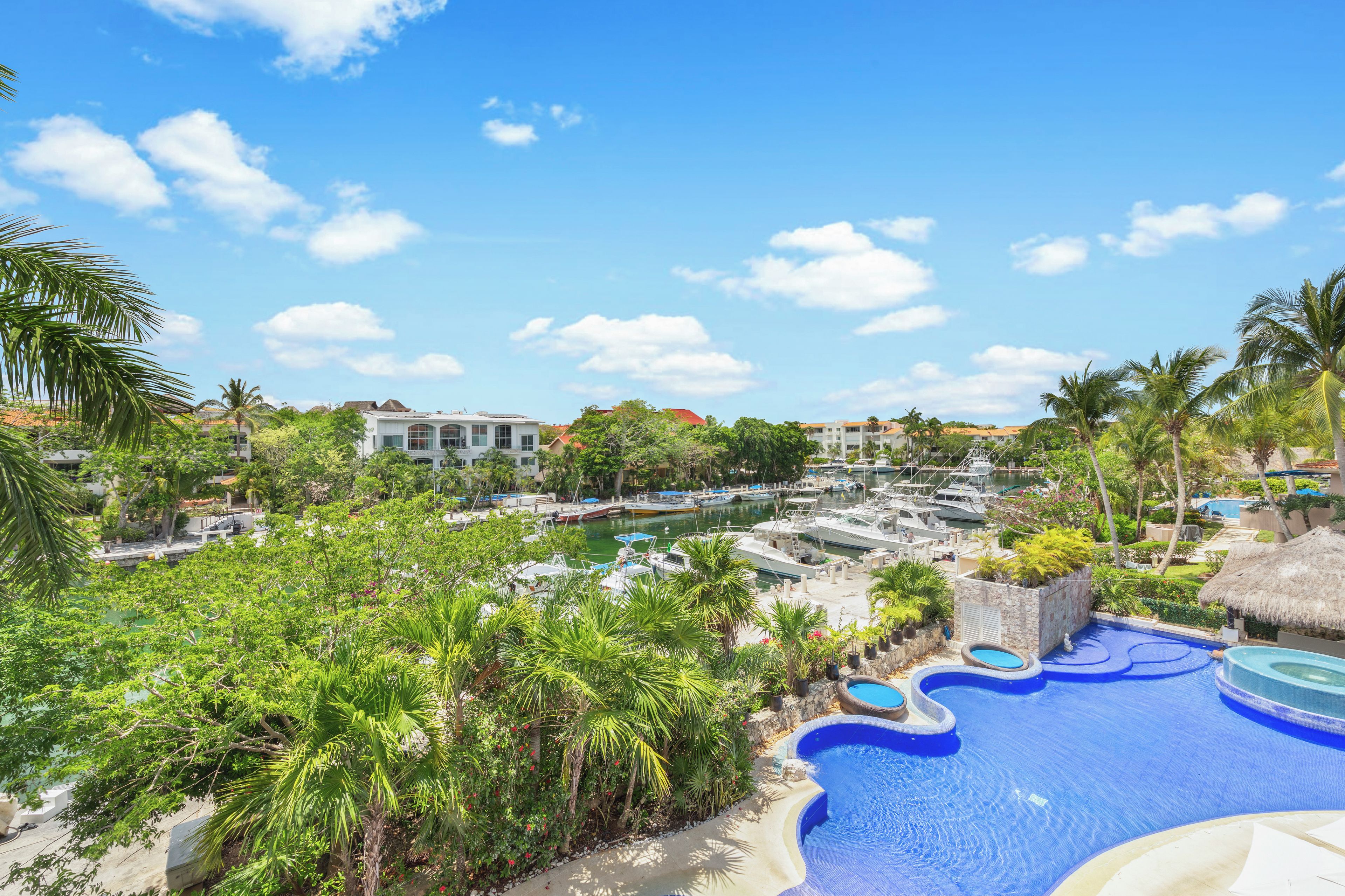Un resort con piscina, barcos y abundante vegetación.