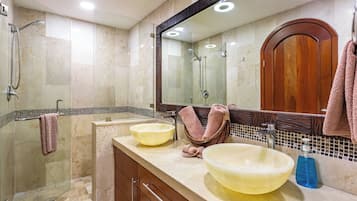Ein modernes Badezimmer mit einer gläsernen Duschkabine, zwei Waschbecken, einem großen Spiegel und Holzschränken.