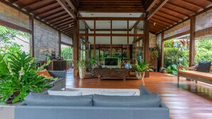 A spacious indoor area with a wooden ceiling, a sofa, and potted plants. - Villa Mulyono (Batu)