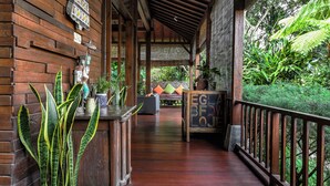 A wooden covered porch with a wooden floor, potted plants, and a sign that reads "EGLA BFDW LOJ". - Villa Mulyono (Batu)