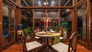 A dining area with a round table, chairs, and a candle centerpiece. - Villa Mulyono (Batu)
