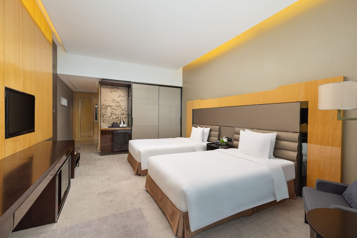 Une chambre d’hôtel avec deux lits, une télévision, un bureau et un coin salon.