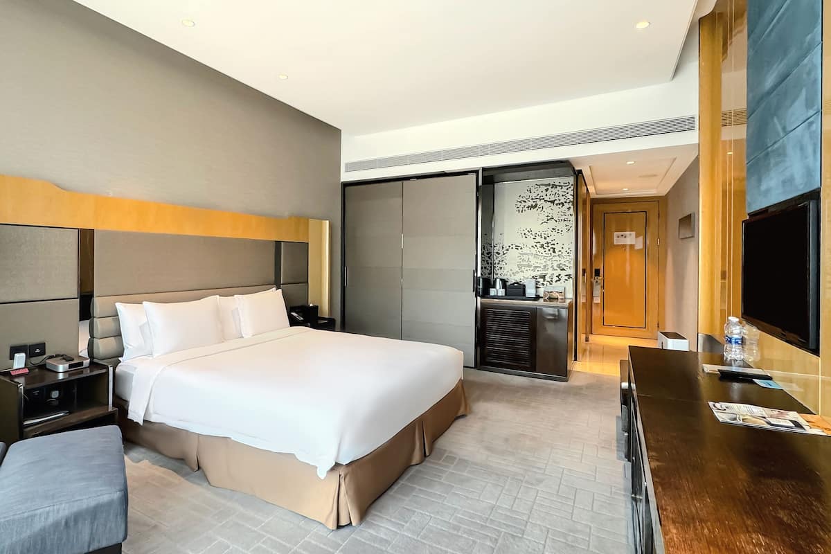 Une chambre d’hôtel avec un grand lit, un bureau, une chaise, une télévision et un mini-bar.