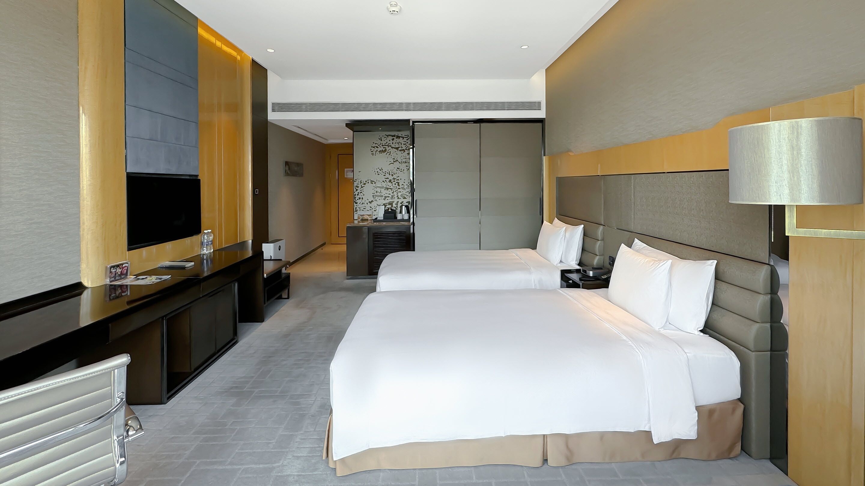 Una habitación de hotel moderna con una cama grande, televisión, escritorio y baño.
