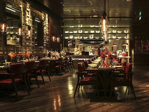 A restaurant with wooden flooring, red upholstered chairs, and hanging pendant lights. - Crowne Plaza Beijing Lido by IHG (Beijing)