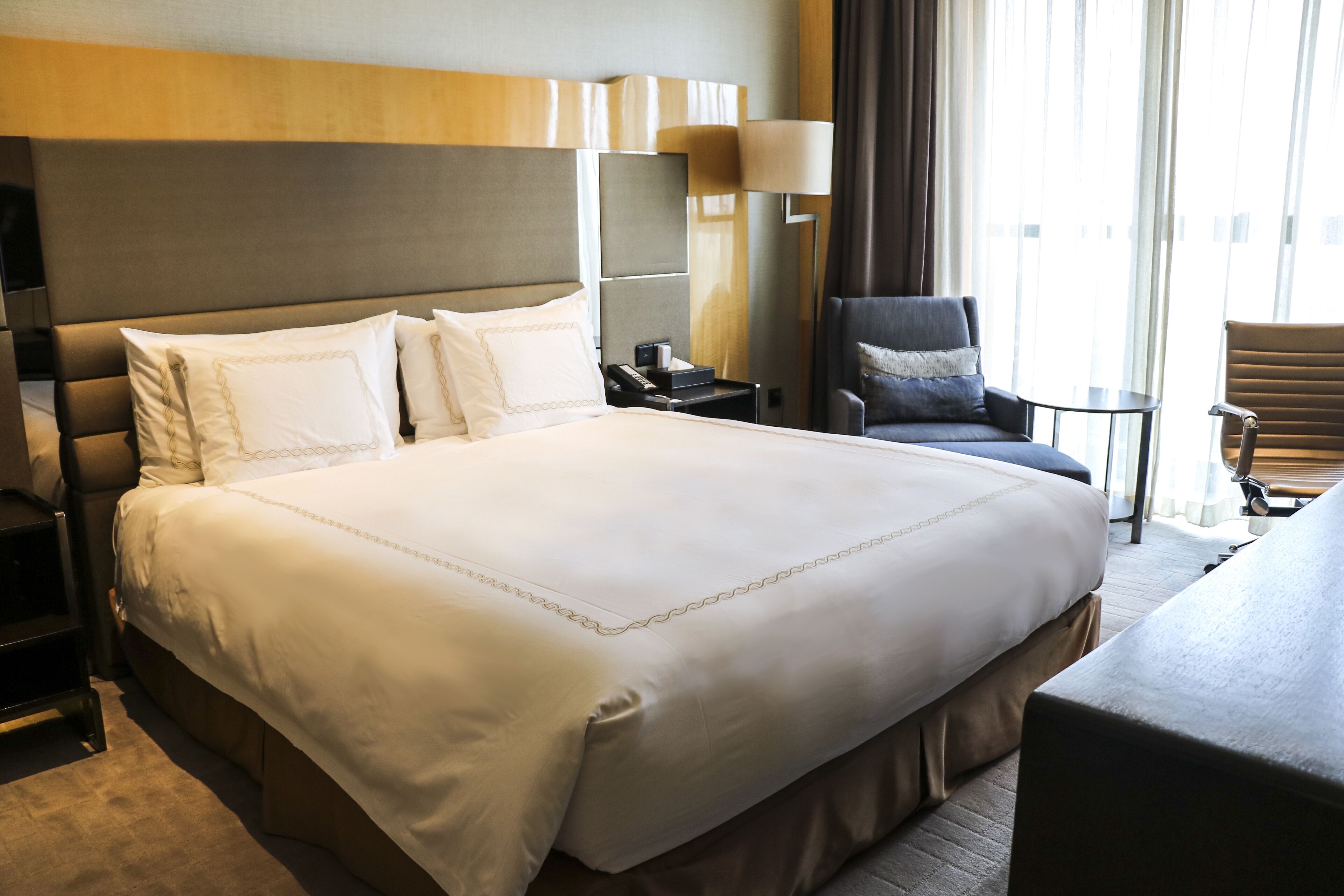 Une chambre d’hôtel avec un grand lit, un bureau, une chaise et une lampe.