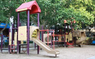 A playground with slides and climbing structures, surrounded by trees.