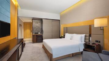 Una habitación de hotel moderna con una cama grande, un televisor, un escritorio y un sofá.