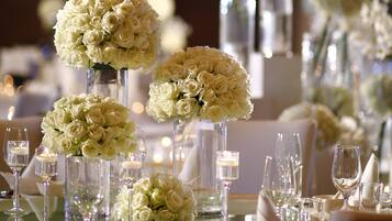 A table set with white roses in tall vases, surrounded by wine glasses and candles.