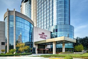En moderne bygning med en buet glasfacade og et skilt med teksten 'CROWNE PLAZA BEIJING LIDO'.
