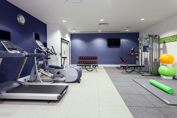 A gym with treadmills, elliptical machines, a weight bench, and a Reebok ball.