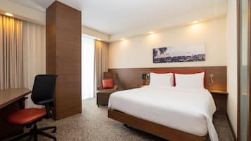 A hotel room with a bed, a desk, and a chair.
