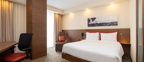 A hotel room with a bed, a desk, and a chair.