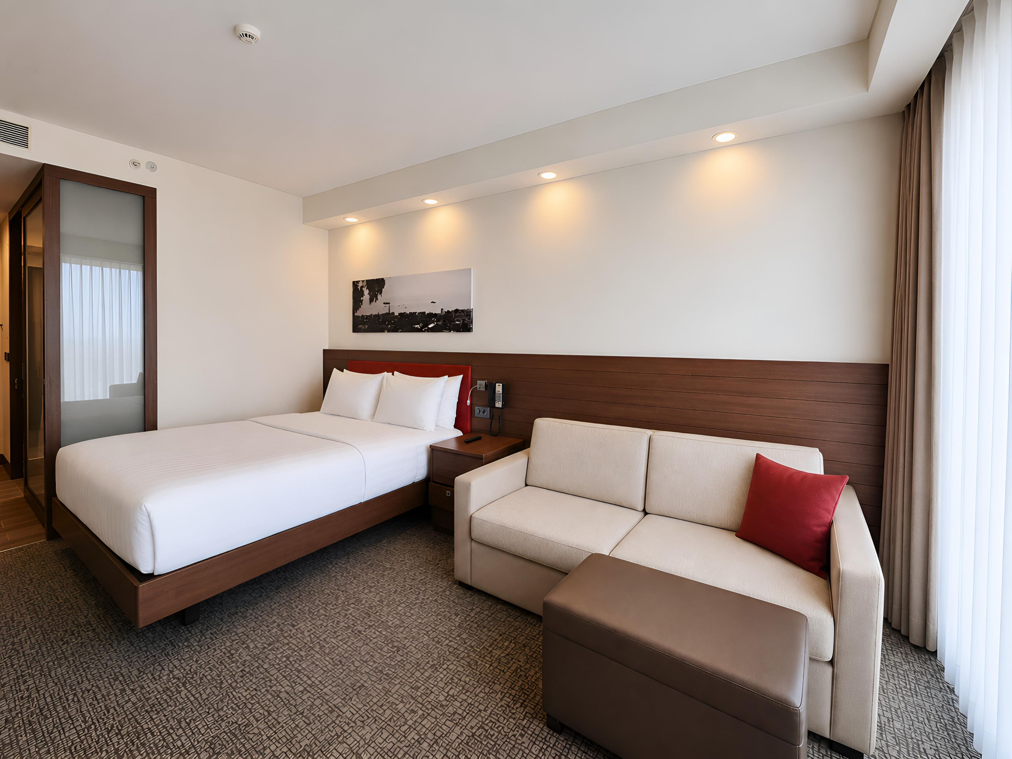 Ein Hotelzimmer mit Bett, einer Couch, einem kleinen Tisch und einem an der Wand befestigten Telefon.
