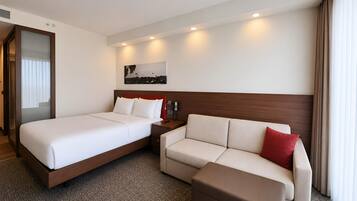 Ein Hotelzimmer mit Bett, einer Couch, einem kleinen Tisch und einem an der Wand befestigten Telefon.
