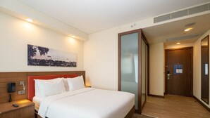 Una habitación de hotel con cama, mesita de noche y un cuadro en la pared.
