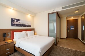 Una habitación de hotel con cama, mesita de noche y un cuadro en la pared.