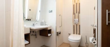 Un baño moderno con lavamanos, espejo, inodoro y ducha.