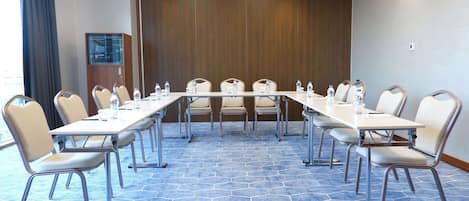 A conference room with a long table, chairs, water bottles, and a wooden panel wall.