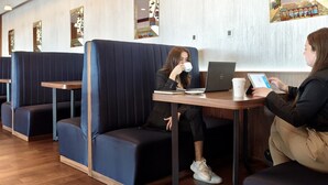 Un área de descanso con asientos tipo cabina, una computadora portátil, una tableta y una taza de café.