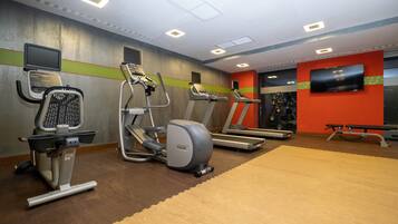 Un gimnasio con cintas de correr, elípticas y bicicletas estáticas.