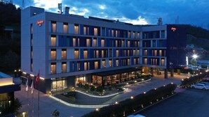 Un hotel moderno con varios pisos, un espacio exterior cubierto y un estacionamiento.