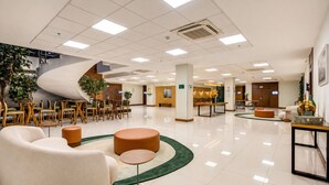 A spacious lobby with a curved staircase, seating areas, and a reception desk.