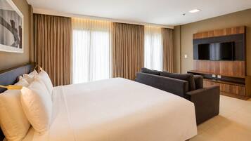 Une chambre d’hôtel avec un grand lit, un canapé, un téléviseur à écran plat et un tableau au mur.