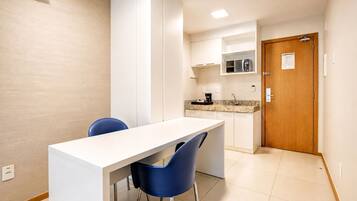 A modern kitchen with white cabinets, a countertop, and a built-in oven. There is a wooden door with a handle and a small window.