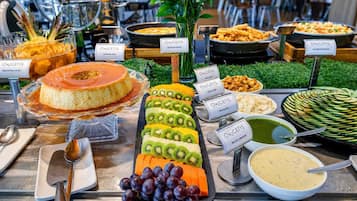 Un buffet con diversi cibi ed etichette, tra cui una torta, frutta e vari piatti.