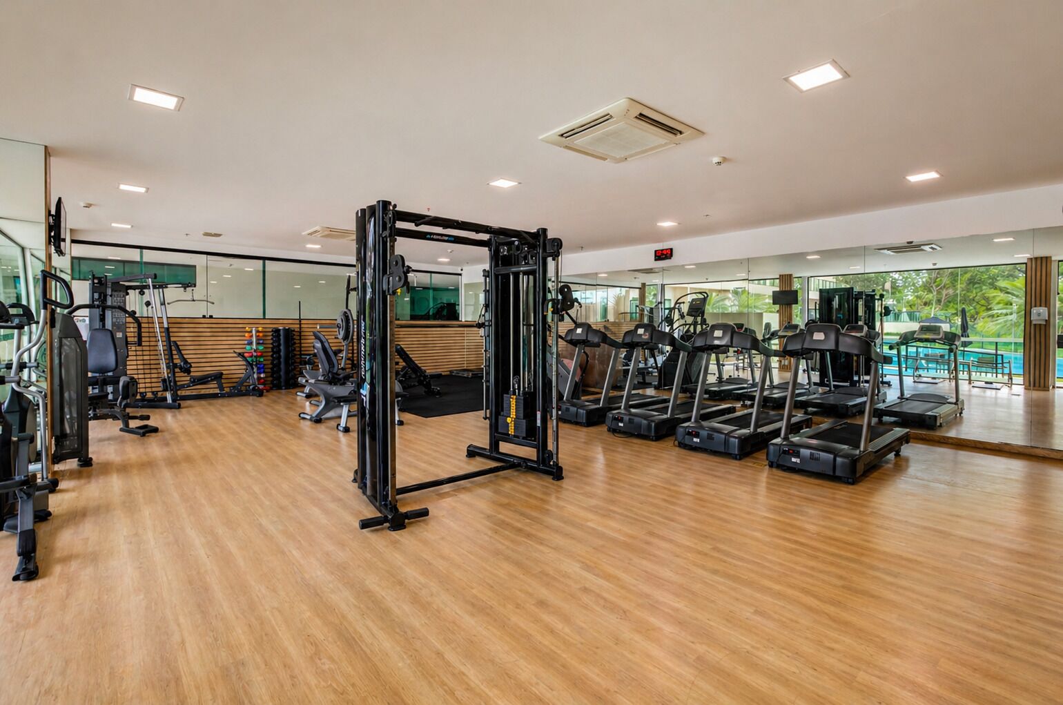 A gym with exercise equipment, a wooden floor, and a large mirror.