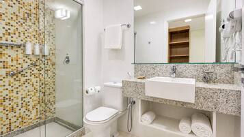 A modern bathroom with a glass shower enclosure, a white toilet, a sink with a mirror, and a towel rack.