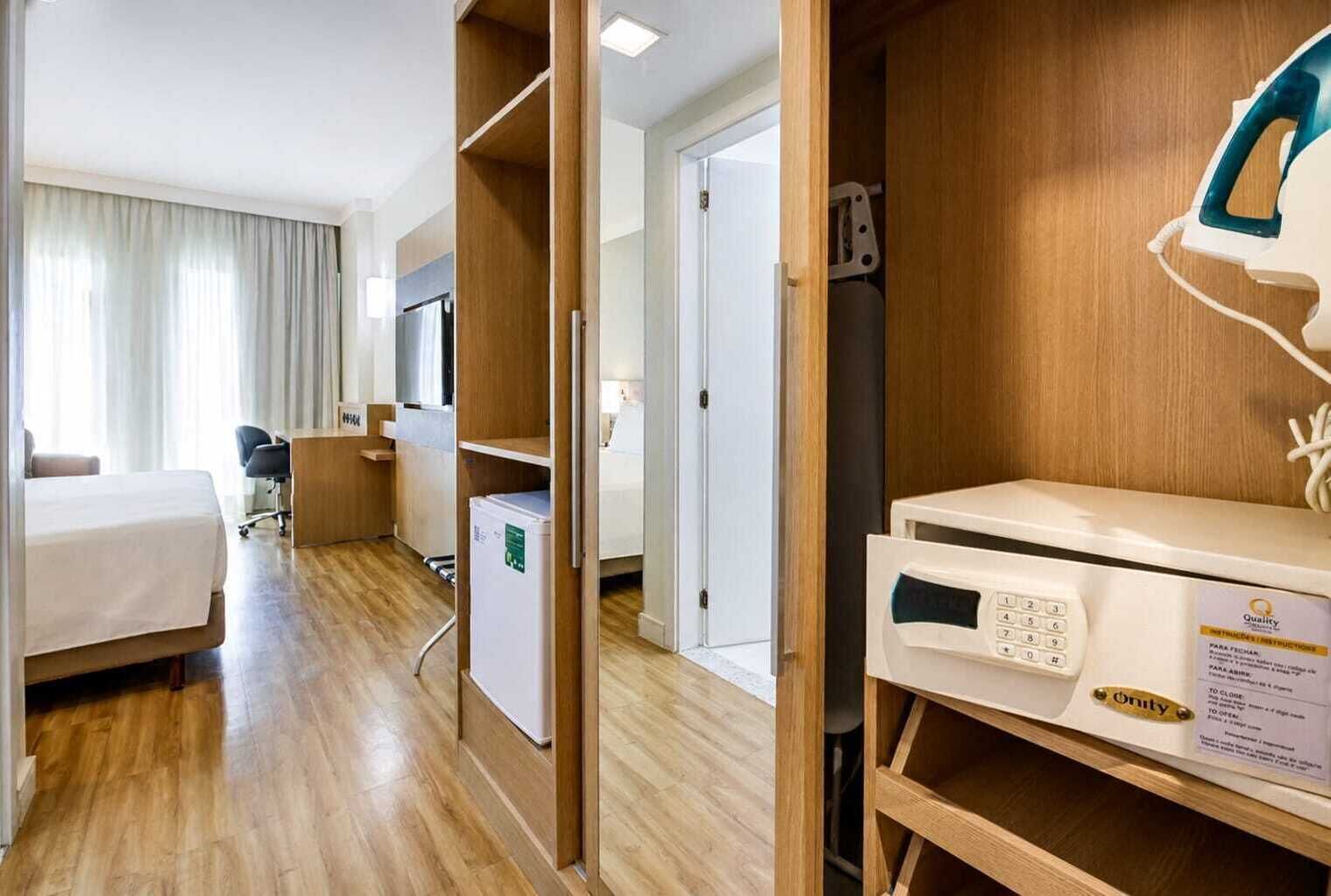 A hotel room with a bed, desk, chair, TV, and a microwave.