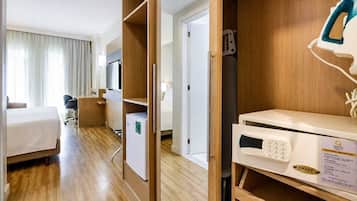 A hotel room with a bed, desk, chair, TV, and a microwave.