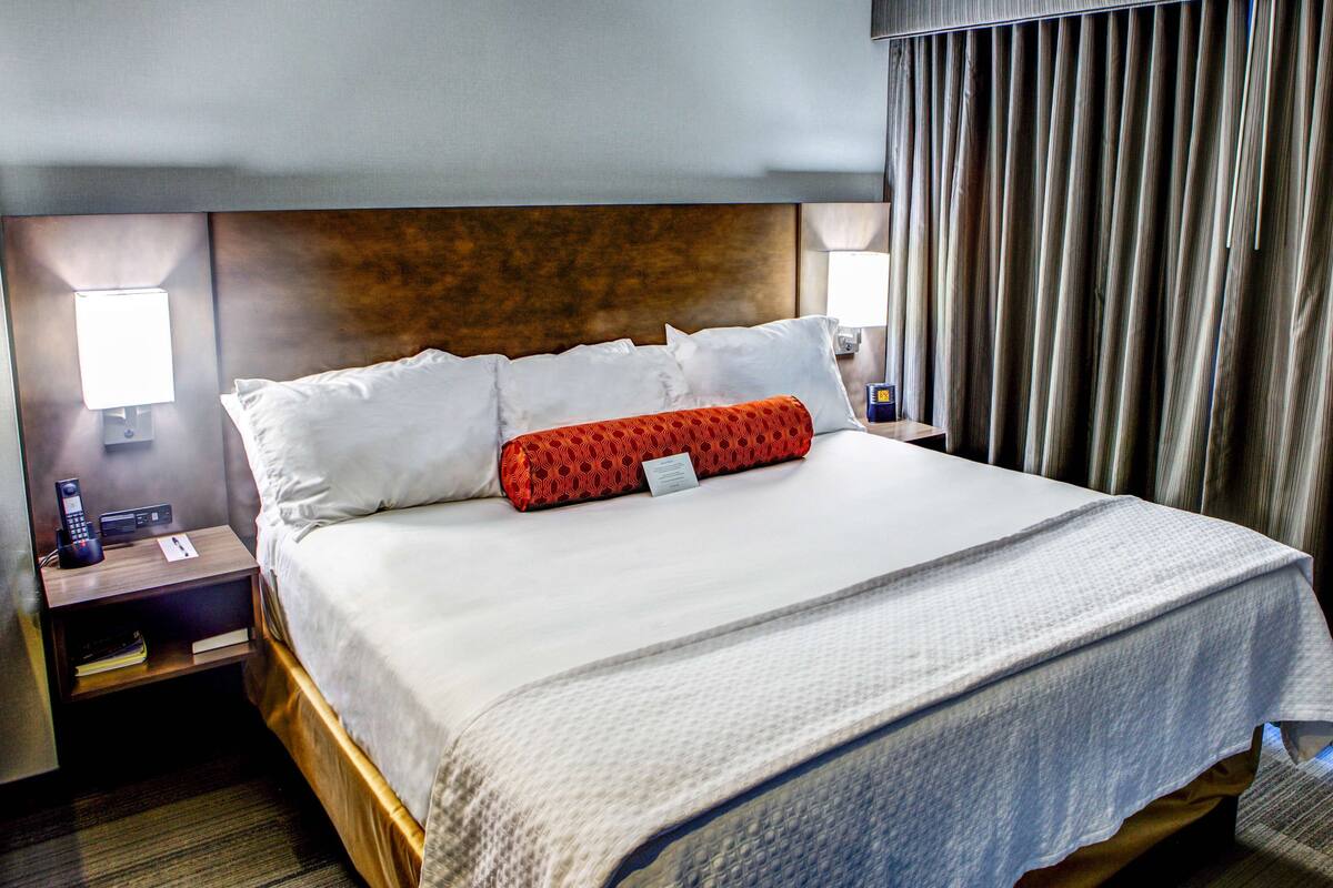A hotel room with a large bed, two bedside tables, a telephone, and a lamp.