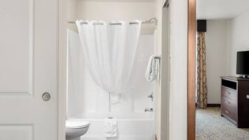 A bathroom with a shower, toilet, and a vanity with a television.