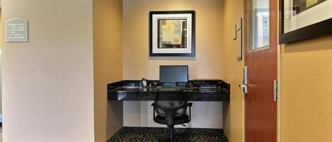 Una habitación de hotel con escritorio, silla y un cuadro en la pared.