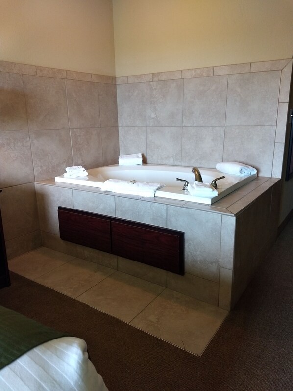 Une salle de bain moderne avec une grande baignoire, un banc en bois et un lavabo encastré.