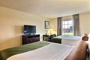 Habitación de hotel con dos camas, televisión, escritorio con silla y ventana con cortinas.