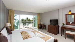 A hotel room with a large bed, a television, a desk, and a balcony with chairs. - Time Out Hotel Beach Front (Patong)