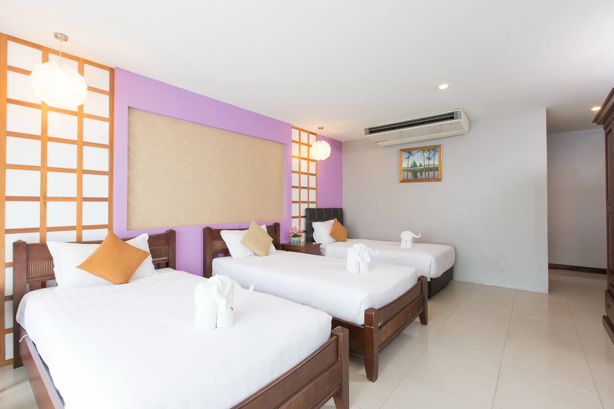 Et hotelværelse med to senge, et stort vindue med udsigt, en aircondition og et billede på væggen.