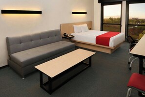 Ein modernes Hotelzimmer mit Bett, Sofa und einem kleinen Tisch.