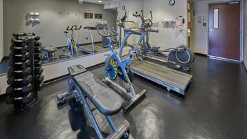 A gym with exercise equipment, a mirror, and a door.