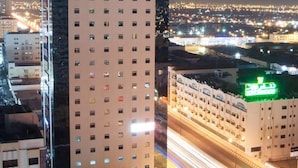 Un immeuble de grande hauteur, surmonté d’une enseigne « Citymax », entouré d’autres bâtiments et bordé par une rue animée où l’on aperçoit des traînées de lumière témoignant de la circulation.